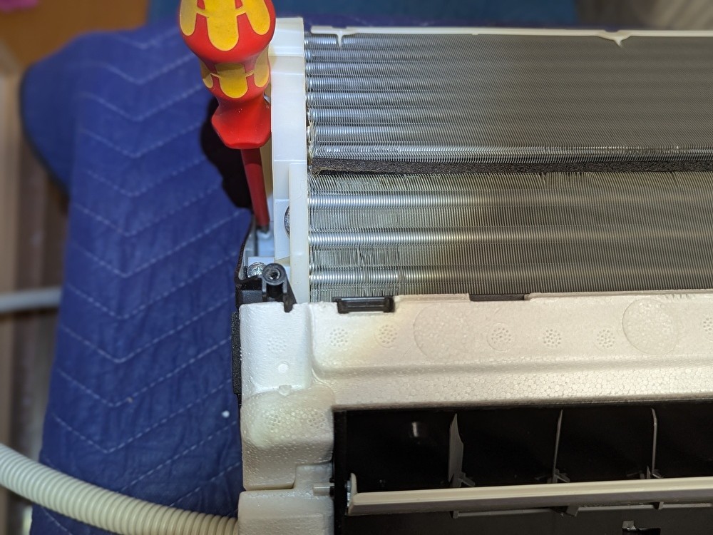 一体となったドレンパンとフィンの固定ネジを外している作業