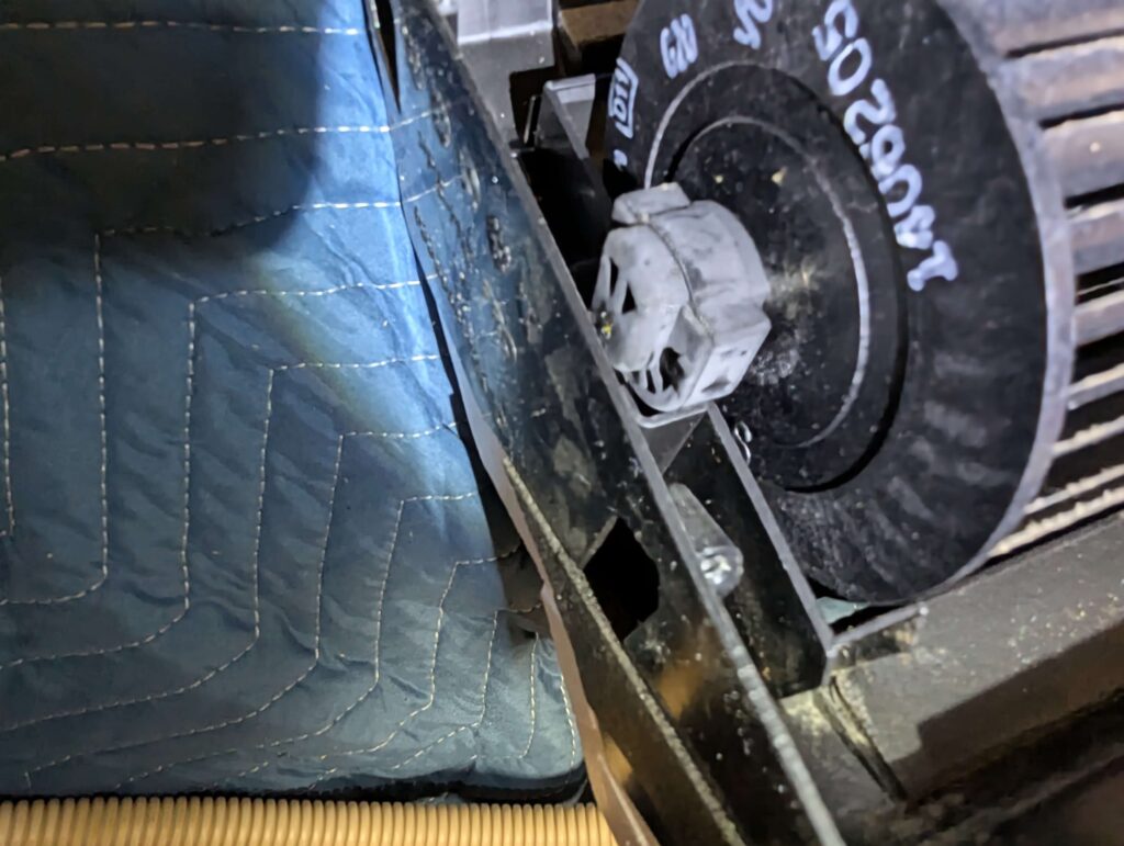 ファンモーターと反対側のファン軸受けをドレンパンから抜いている作業