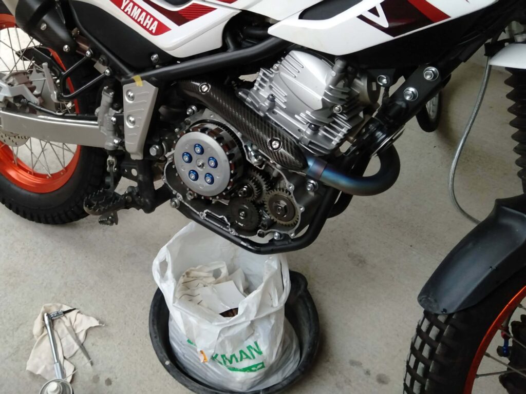 セロー250の古いオイル排出時 – 熱で劣化しかなり黒くなっていたので念のためクラッチカバーを外してクラッチの様子を確認している様子