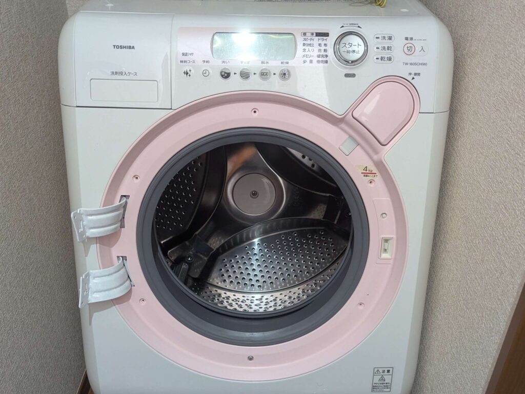 東芝 TW-160SCH ドラム式洗濯機の分解Step1・ドア取り外し完了状態。外装カバー分解の最初の手順。続いてドア回りカバー（ピンク）・前面下部カバー（キックプレート）・操作パネル・トッププレート・前面カバー（大）の順に取り外していく