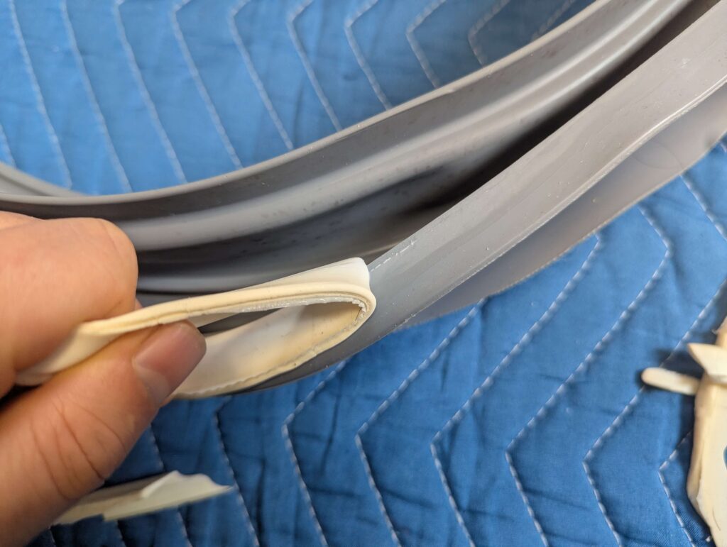 東芝 TW-160SCH ドラム式洗濯機のドアパッキン再取り付け前に、元から塗られていた古いシリコンシーラントを取り除いている状態。新しいシリコンシーラントを塗り直すための下地処理。古いシーラントの完全除去が水漏れ防止の前提