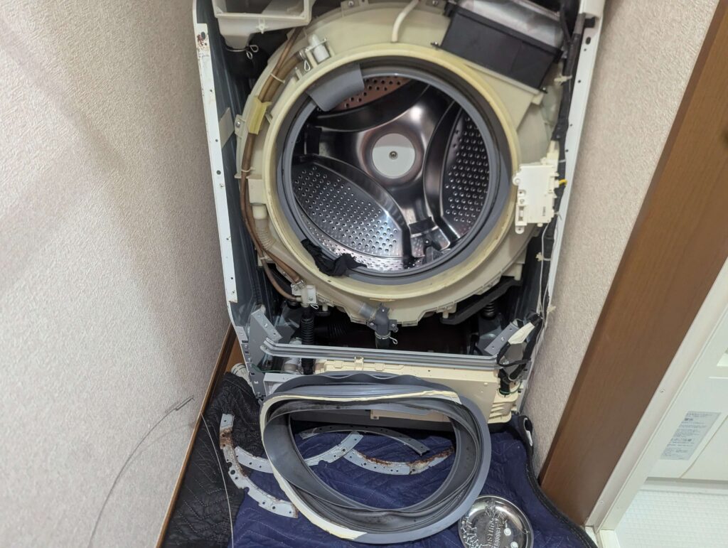 東芝 TW-160SCH ドラム式洗濯機のスプリングワイヤーを外してドアパッキンを取り外した状態。外槽前カバーへのアクセスが可能になった。合いマークを刻んだ後に取り外した状態。パッキンは過炭酸ナトリウム温水に一晩漬け置き洗浄へ