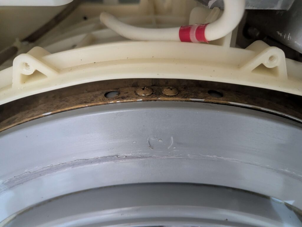 東芝 TW-160SCH ドラム式洗濯機の洗濯槽(ドラム)外側に蓄積した柔軟剤・洗剤カスのヘドロ汚れの清掃前(Before)。洗濯槽が外れなかったため、外槽との隙間から届く範囲をブラッシング洗浄。