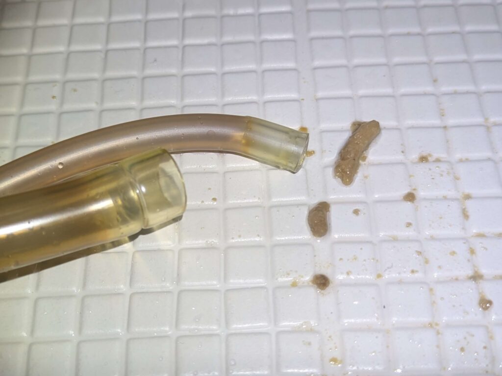 東芝 TW-160SCH ドラム式洗濯機の循環ホースをチューブブラシで清掃後にエアガンで吹いた際に排出された柔軟剤・洗剤カスのヘドロ状固形物。19年分の汚れが蓄積した循環経路の汚染度合いを示す実例。黒いワカメの発生源のひとつ