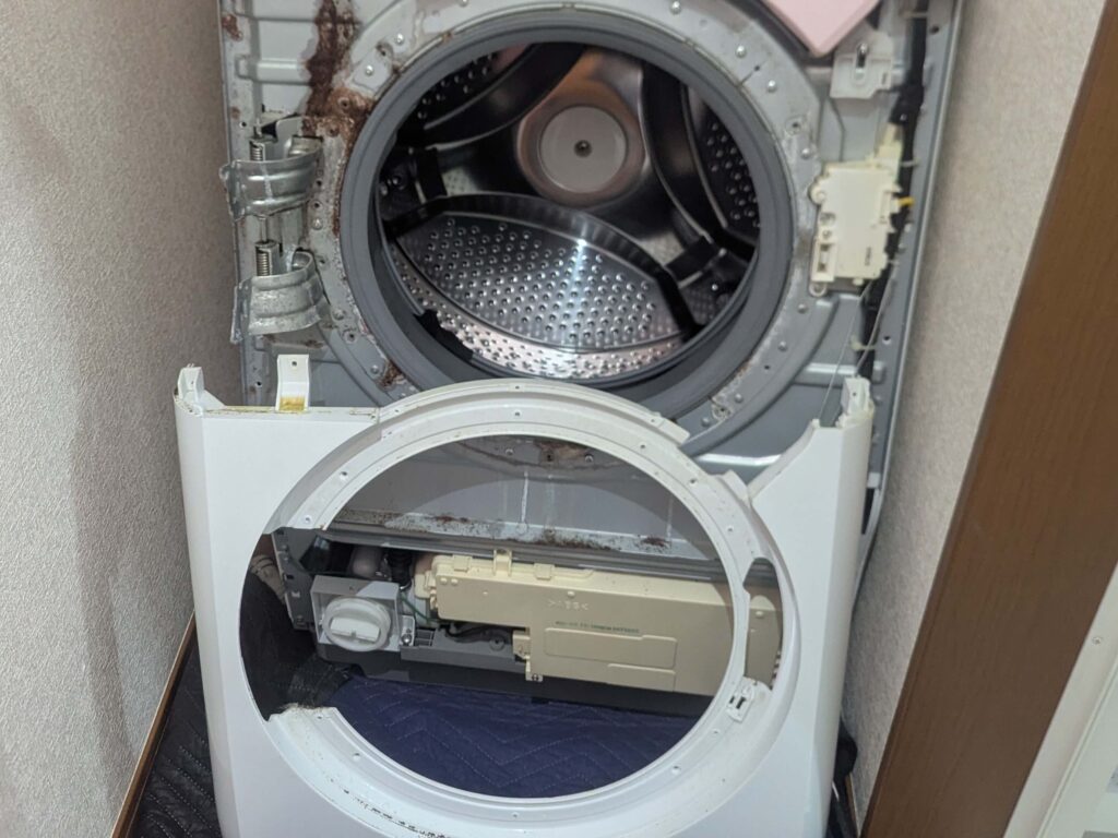 東芝 TW-160SCH ドラム式洗濯機の前面カバー(大)を取り外した状態。外槽前カバー・ドアパッキン押えプレート・ヒーターユニットへのアクセスが可能になった状態。分解Step1の外装取り外し完了