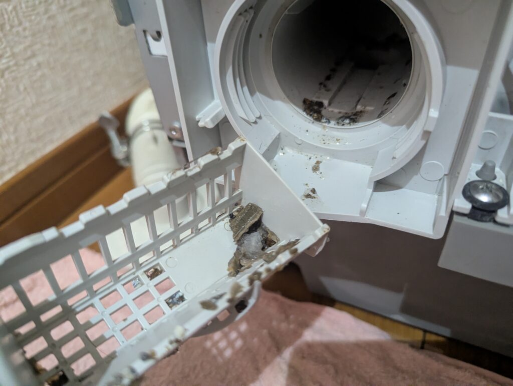 東芝 TW-160SCH ドラム式洗濯機の糸くずフィルターに落ちてきた蓄積された柔軟剤（洗剤）の剥離片とサビ片