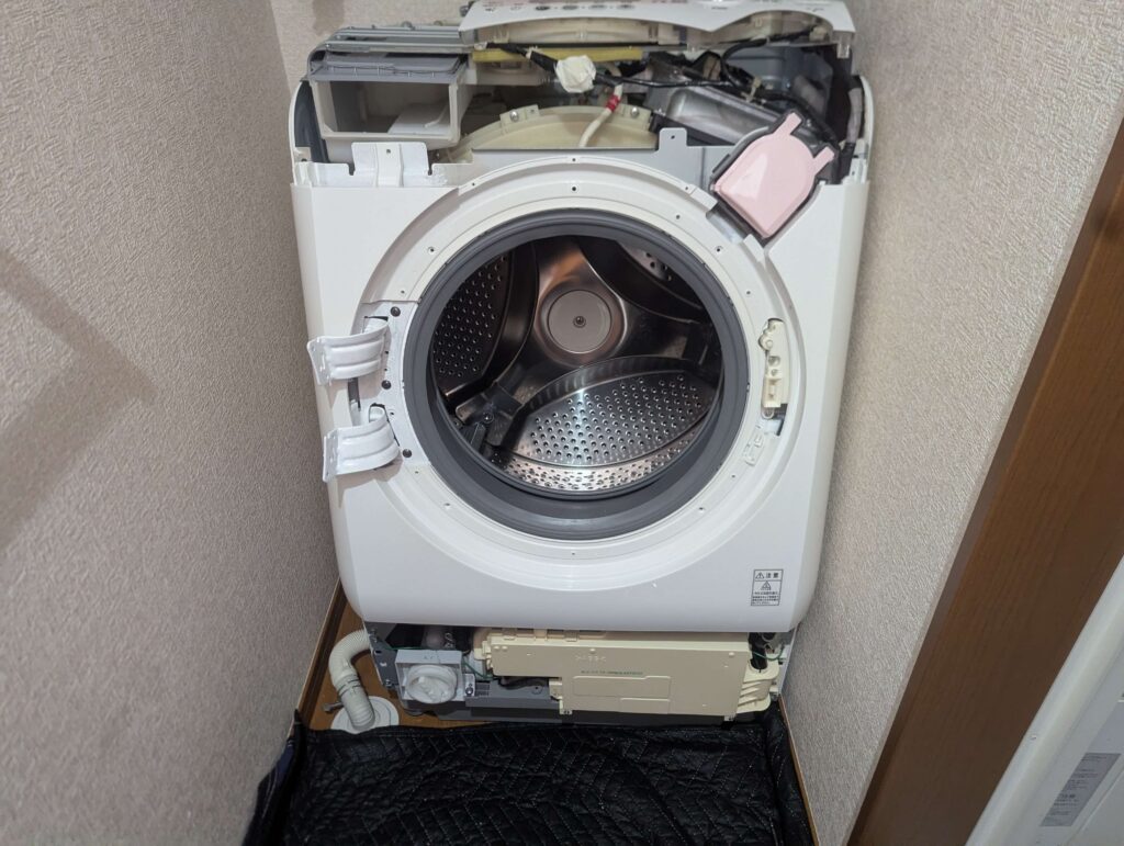 東芝 TW-160SCH ドラム式洗濯機の前面カバー(大)をドア開閉確認用の磁気センサーとともに取り付ける前の状態。磁気センサーのはめ込みを忘れると扉開閉エラーが発生するため必須の確認事項