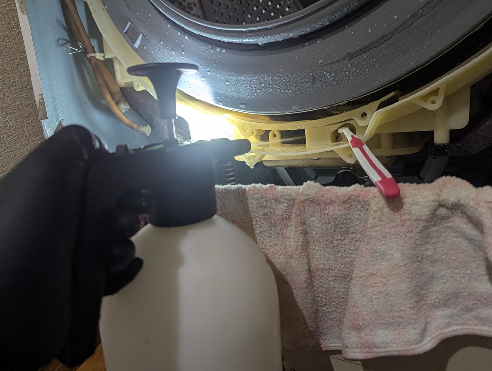 東芝 TW-160SCH ドラム式洗濯機の外槽(水槽)内壁と洗濯槽(ドラム)外側に蓄積した柔軟剤・洗剤カスのヘドロ汚れを清掃中。過炭酸ナトリウム・クエン酸・重曹を噴霧器で吹き付けてブラッシング洗浄。分解できなかった洗濯槽と水槽の隙間を届く範囲で清掃。ドレンパンの黒いスライムも同時除去