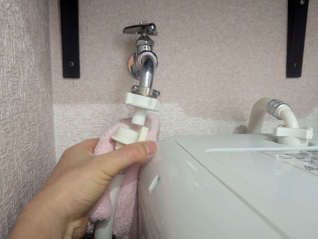 東芝 TW-160SCH ドラム式洗濯機のトッププレート取り外しに先立って給水ホースを外している状態。トッププレートを外す前に給水ホースを先に切り離す必要がある。分解時の水漏れ防止のための手順