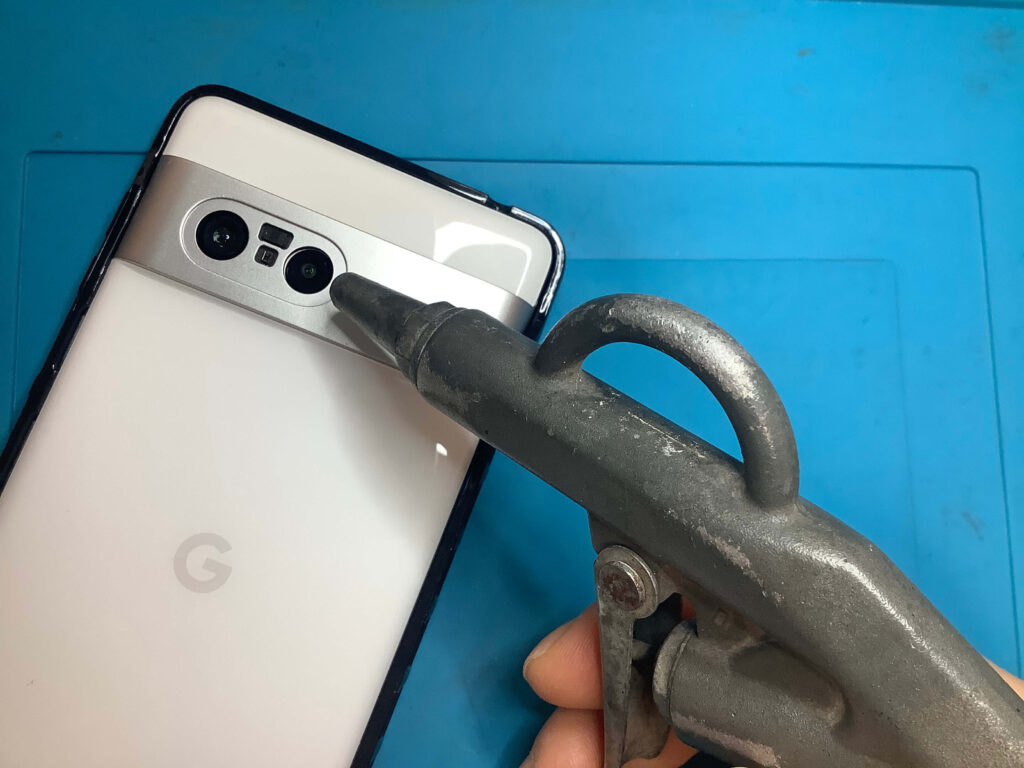 エアダスターを超広角カメラ側の隙間から吹き込み、センサーのゴミを吹き飛ばす様子