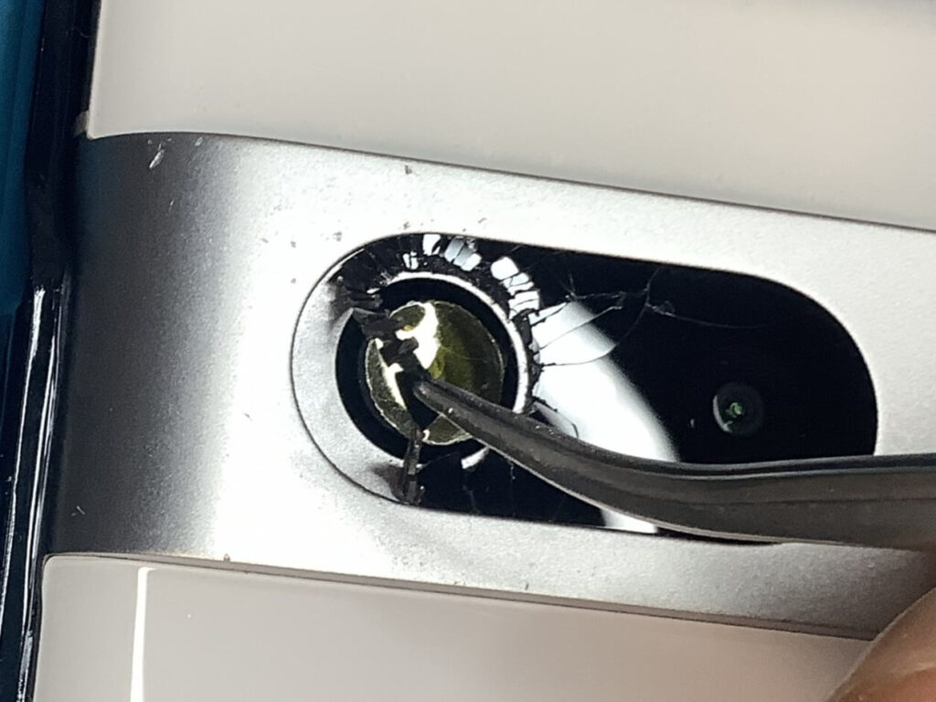 ピンセットを使って古い粘着テープごと割れたカメラガラスを剥がす様子