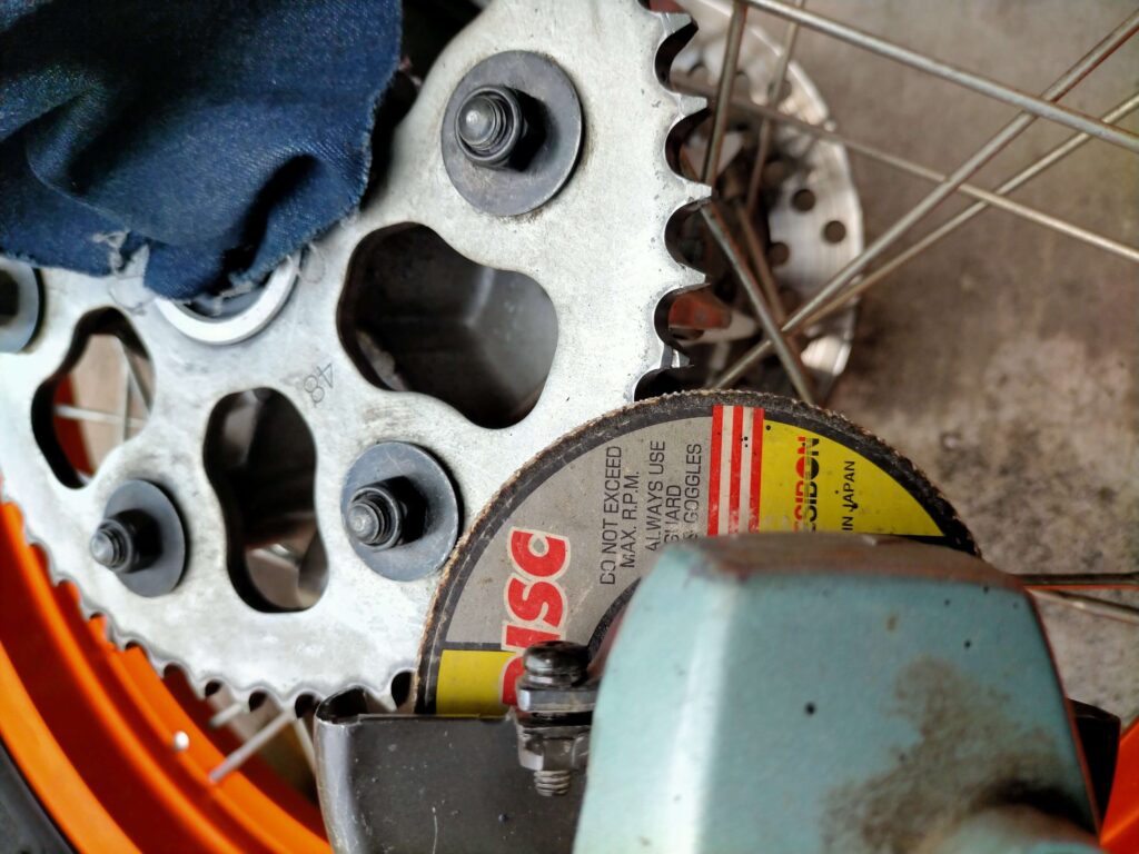 ガレ場でついたセロー250のスプロケット打痕をグラインダーとヤスリで削ってDIY修整する作業風景