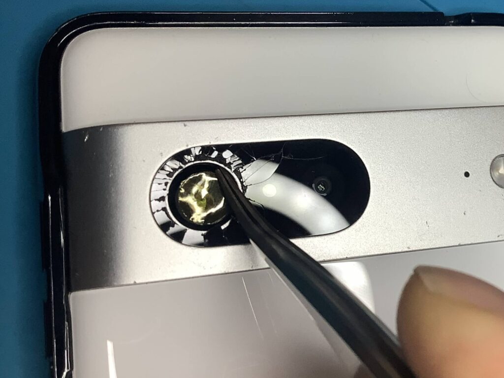 ピンセットでポリイミドテープを押さえつけ、カメラレンズ周辺の隙間を塞ぐ作業