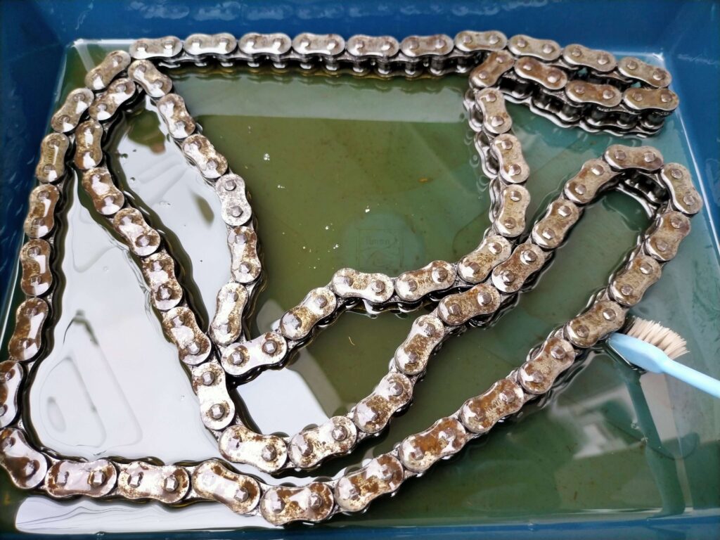 エンジンオイルと歯ブラシを使ってセロー250のシールチェーンを徹底洗浄する様子