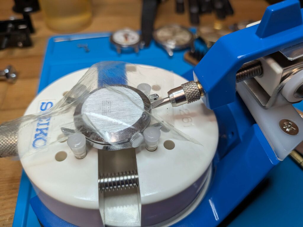 裏蓋オープナー工具を使ってBRADLEY社製ミッキーマウス首振り腕時計の裏蓋を開ける様子