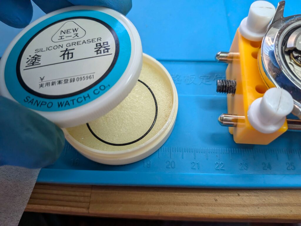 専用の塗布器を使いシリコンオイルを塗布したオリエント・キングマスター(EM00-C2)の裏蓋パッキン