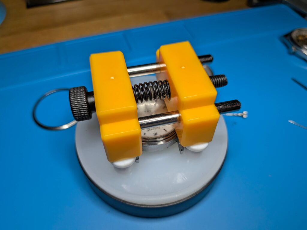 時計ケースの裏側にクッションケースをあてがい全体をひっくり返してセイコー5アクタスのムーブメントを慎重に取り出している様子
