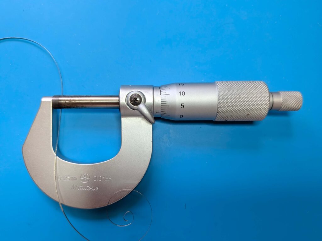 ミツトヨ製のマイクロメーターを使ってゼンマイの厚みを100分の1ミリ単位で精密計測している様子