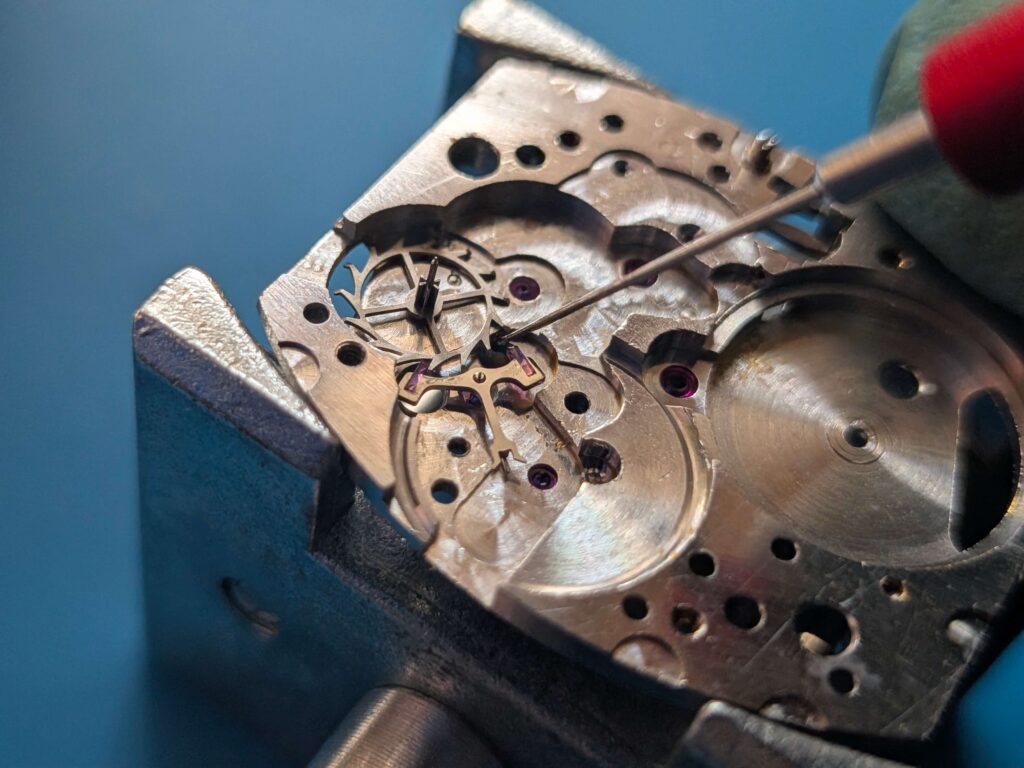 ムーブメントに組み込んだアンクルの爪石(ルビー)へ、オイラー(注油工具)を使って精密油を極少量注油する工程
