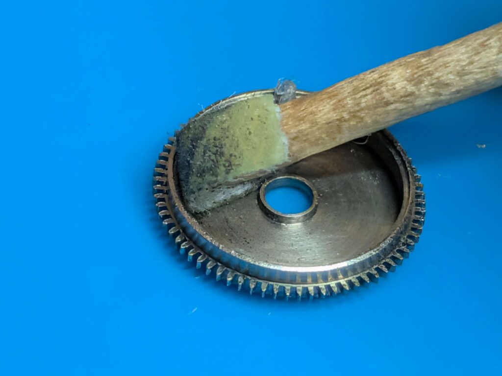 新しいゼンマイが滑らかに動くよう耐水ペーパー800番で香箱の傷ついた内壁を磨いて整える様子