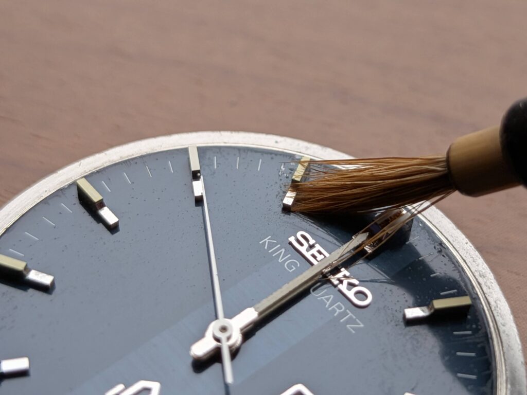 柔らかい筆を使って11時インデックスのカビを慎重に払い落とす作業