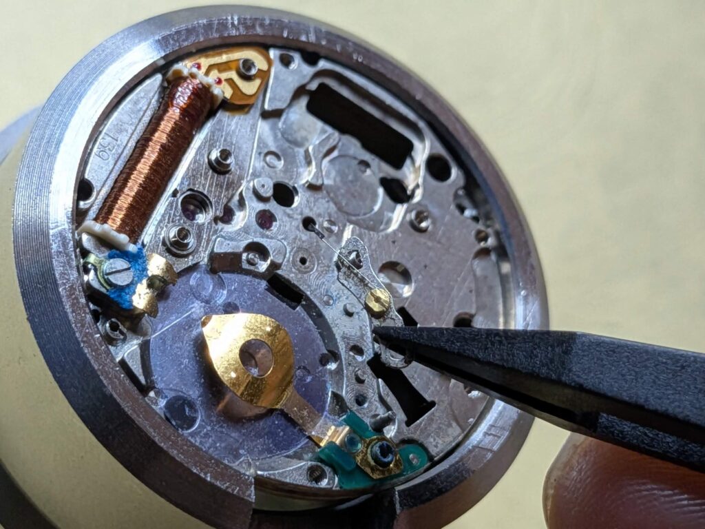 ピンセットを使用してムーブメント内の小さなレバー部品を取り外す様子
