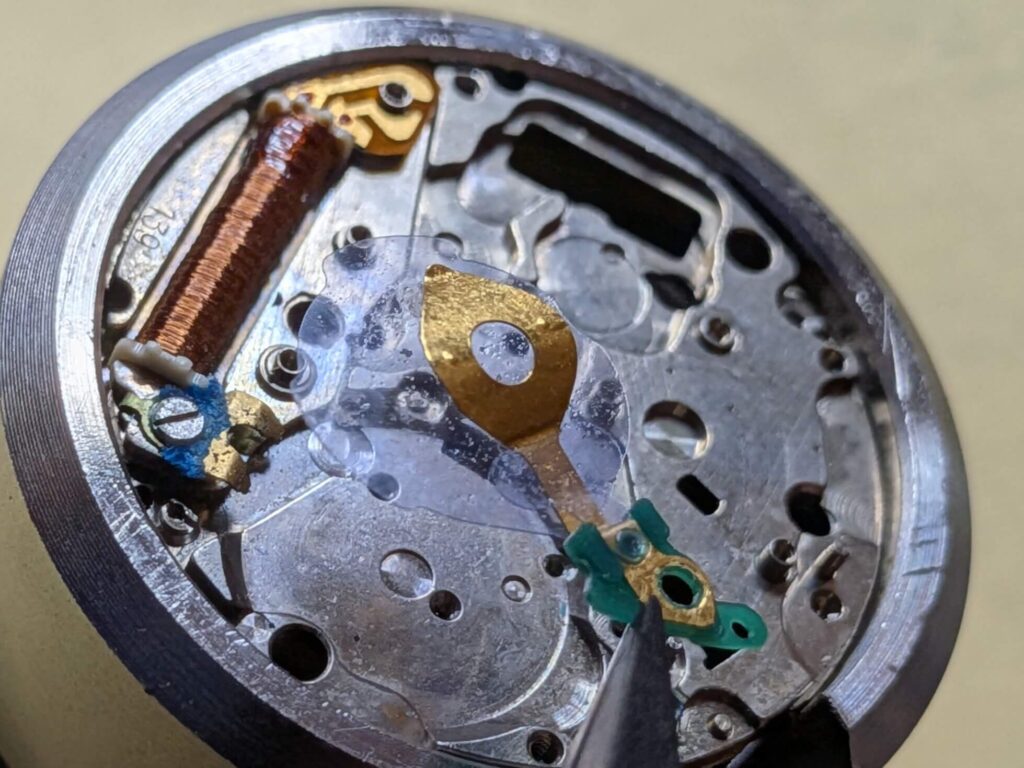 ピンセットでバッテリーのマイナス端子をつまみ上げて取り外す分解作業